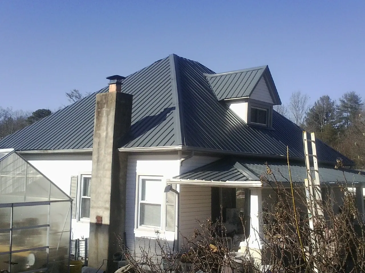Dark blue standing seam metal roof on a white farmhouse with dormer — Slate & Tile Roof Repair by Roofing Brothers in Slate Run