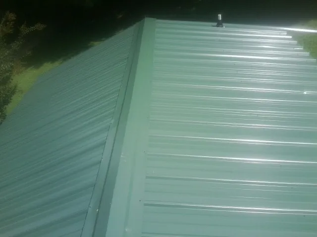 New green metal panels meeting at the ridge of a roof — Flat Roof Repair work by our crew in Slate Run