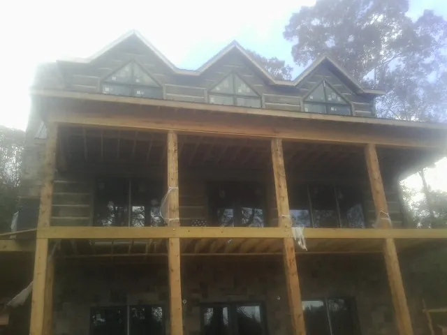 Dormers and porch framing on a large log home under construction — Roof Coating work by our crew in Slate Run