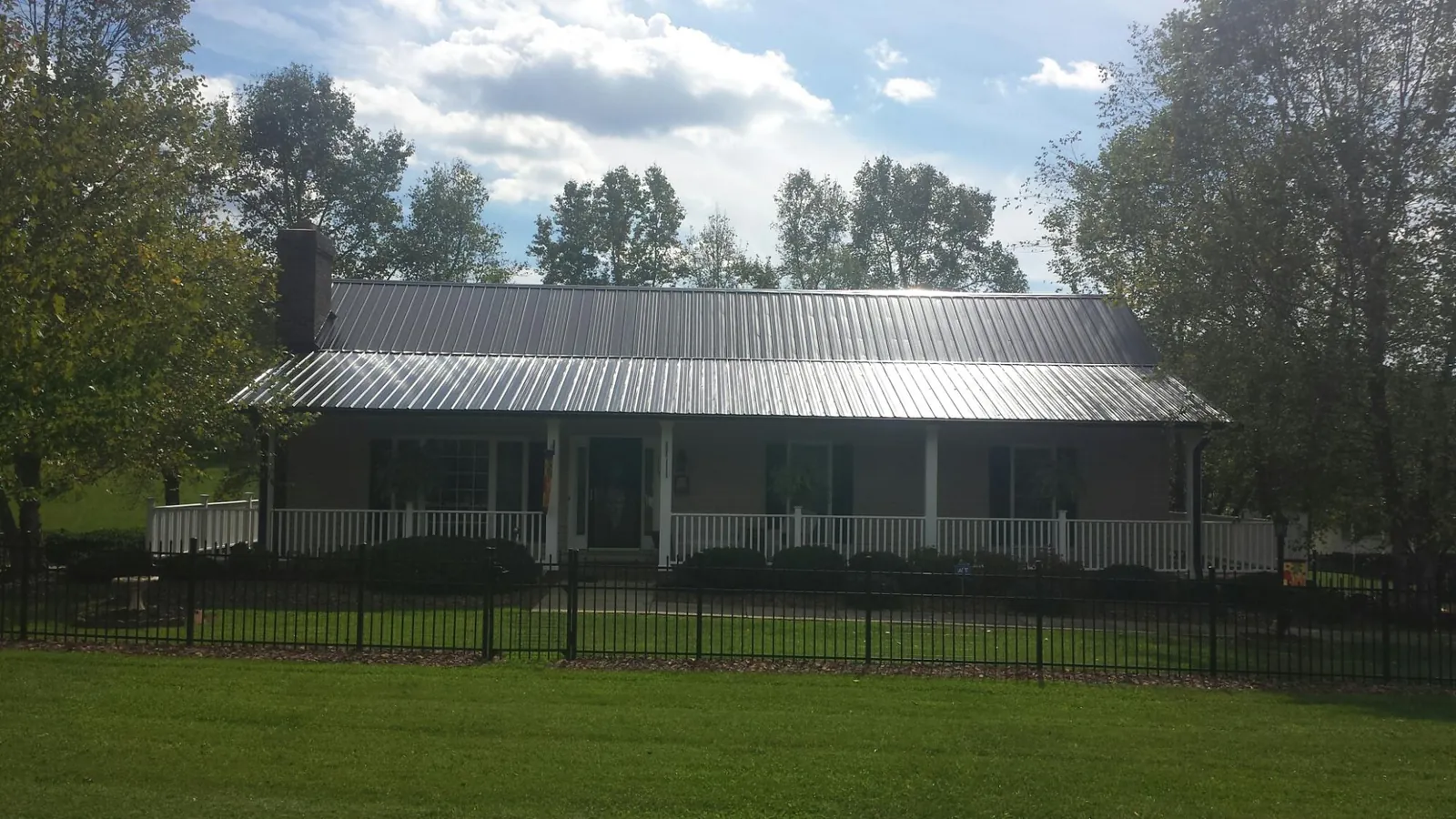Gray metal roof on a brick ranch with a full width front porch — Gutter Guard Installation work by our crew in Slate Run