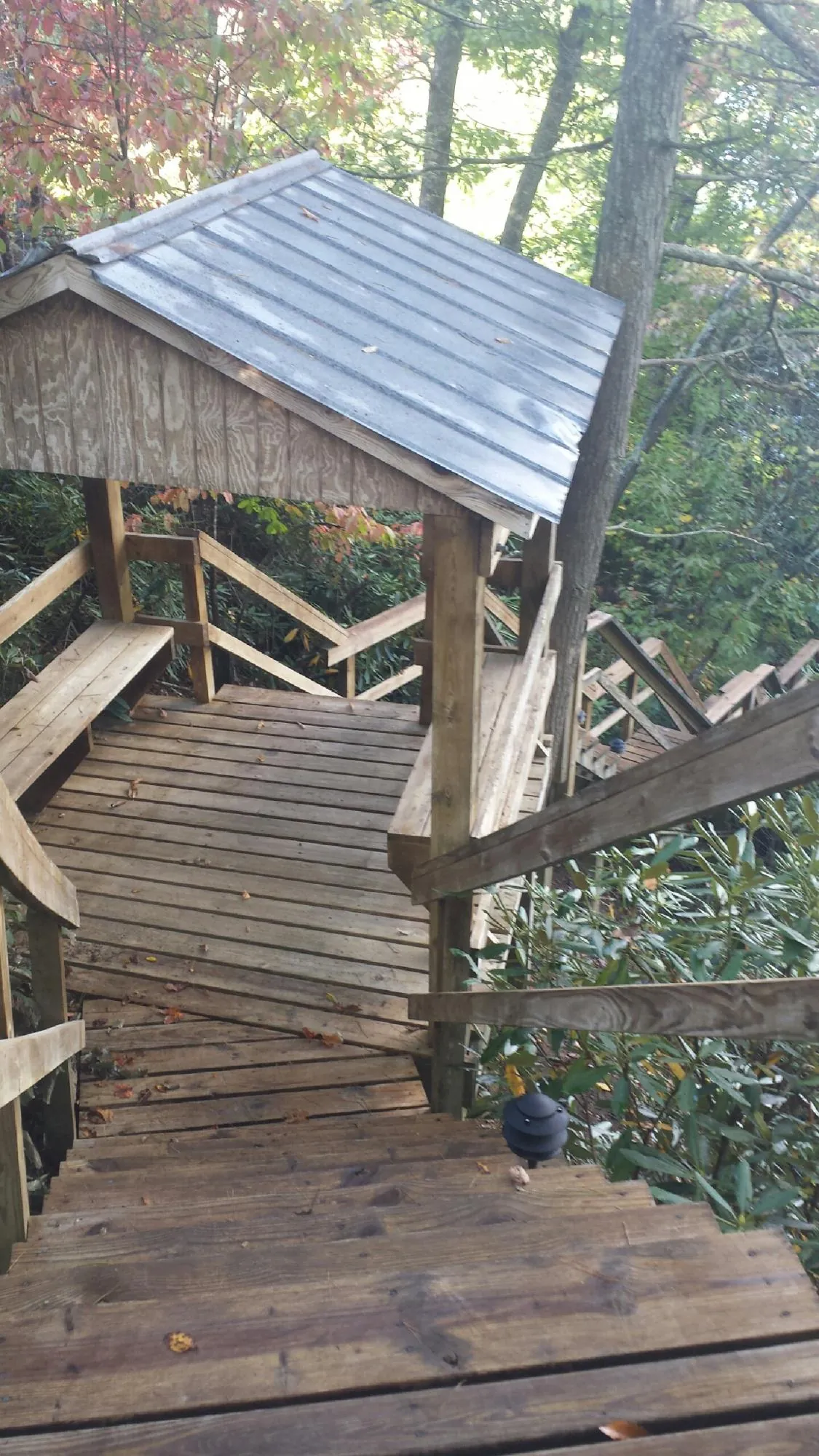 Metal roofed shelter over wooden steps on a wooded walkway — Skylight Repair & Installation work by our crew in Slate Run
