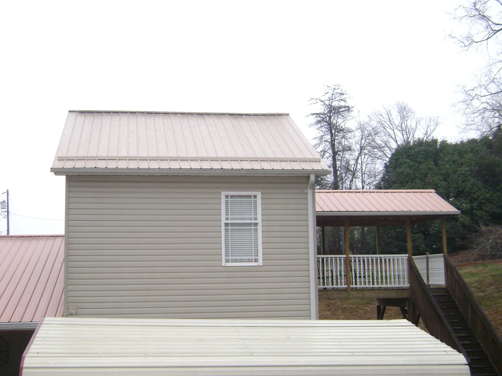Tan metal roofs on a two story addition and attached porch, from a Roof Replacement job in Slate Run