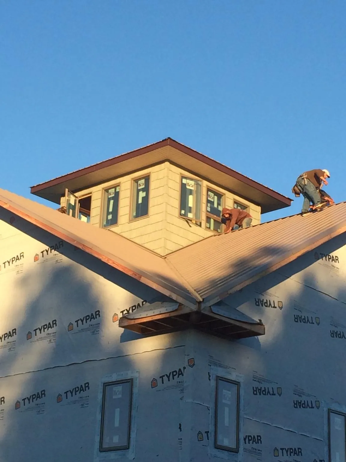 Roofers working around a rooftop cupola on a new metal roof at sunset — Roof Waterproofing in Slate Run by Roofing Brothers